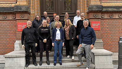 Participants in the NFDI strategy workshop smiling for a group photo on the steps outside the Einstein Center Digital Futures in Berlin.