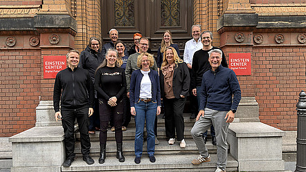 Participants in the NFDI strategy workshop smiling for a group photo on the steps outside the Einstein Center Digital Futures in Berlin.